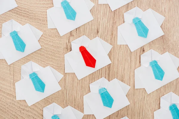 Top view of origami white shirts with blue ties with one red on wooden surface — Stock Photo