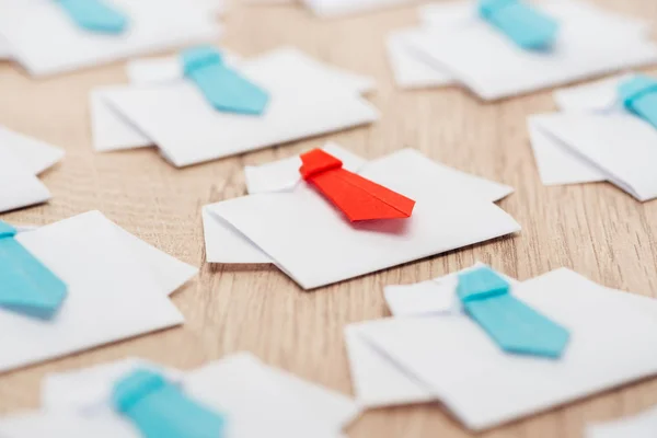 Foco seletivo de origami camisas brancas com laços azuis com um vermelho na mesa de madeira — Fotografia de Stock