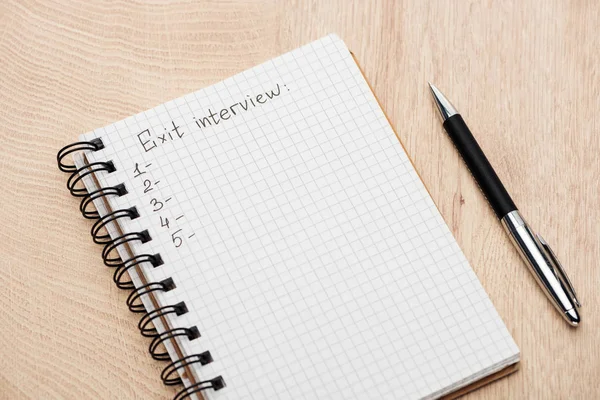 Cuaderno con bolígrafo, letras de entrevista de salida y números en la mesa de madera - foto de stock