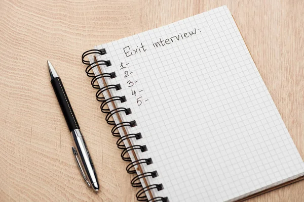 Notebook with exit interview lettering, copy space and numbers on wooden table near pen — Stock Photo