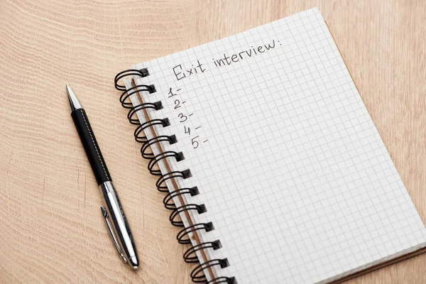 Cuaderno con letras de entrevista de salida, espacio para copiar y números en la mesa de madera cerca de la pluma - foto de stock