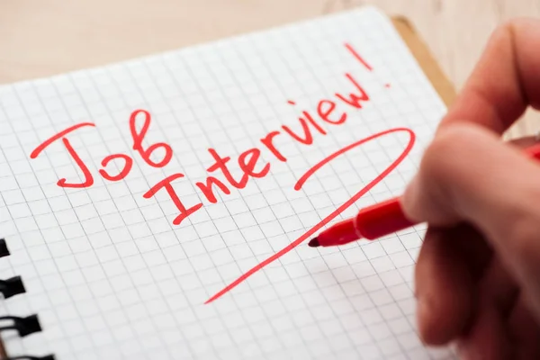 Vista recortada del hombre escribiendo en cuaderno con letras de entrevista de trabajo rojo - foto de stock