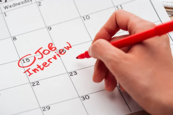 Cropped view of man writing with red marker on print calendar with job interview lettering — Stock Photo