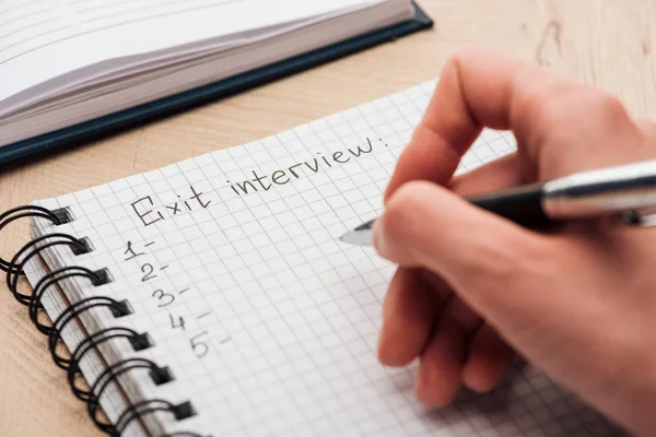 Ausgeschnittene Ansicht des Recruiters, der in Notizbuch mit Exit-Interview-Schriftzug schreibt — Stockfoto