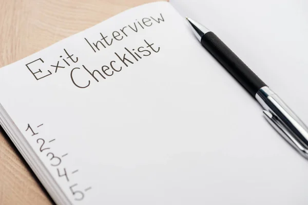 Close up of notebook with exit interview checklist lettering and pen — Stock Photo