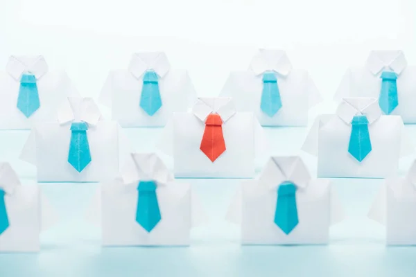 Origami camisas brancas com laços azuis com um vermelho no fundo azul, pensar conceito diferente — Fotografia de Stock