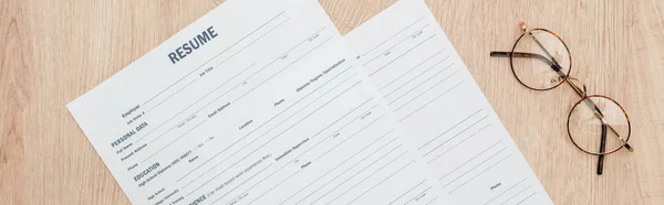Panoramic shot of resume templates and glasses on wooden surface — Stock Photo