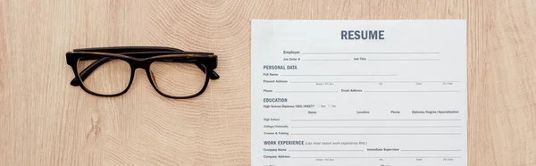 Panoramic shot of resume template and glasses on wooden surface — Stock Photo