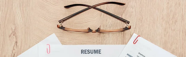 Panoramic shot of print resume templates and glasses on wooden table — Stock Photo