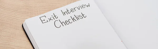 Panoramic shot of notebook with exit interview checklist lettering on wooden table — Stock Photo