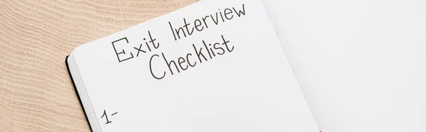 Panoramic shot of notebook with exit interview checklist lettering and number on wooden table — Stock Photo