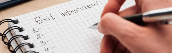 Panoramic shot of recruiter writing in notebook with exit interview lettering — Stock Photo