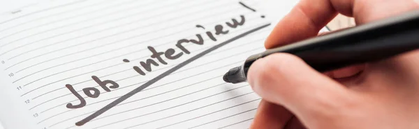 Panoramic shot of man writing in notebook with black job interview lettering — Stock Photo