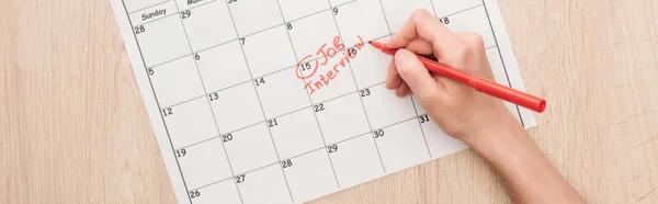 Panoramic shot of recruiter writing with red marker on print calendar with job interview lettering — Stock Photo