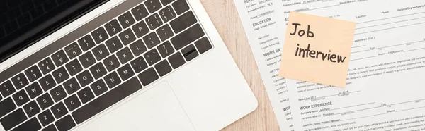 Panoramaaufnahme von Laptop, Lebenslauf-Vorlagen und Haftnotiz mit Jobinterview-Schriftzug auf Holztisch — Stockfoto