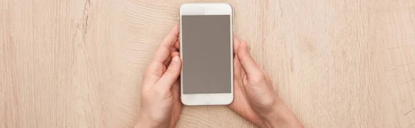 Panoramic shot of woman holding smartphone with blank screen in hands — Stock Photo