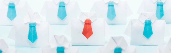 Colpo panoramico di origami camicie bianche con cravatte blu con uno rosso su sfondo blu, pensare concetto diverso — Foto stock