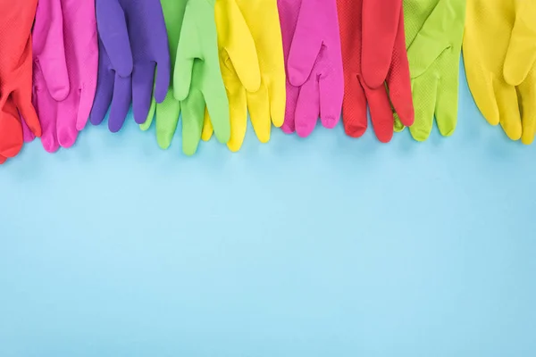 Різнокольорові гумові рукавички на синьому фоні з копіювальним простором — стокове фото