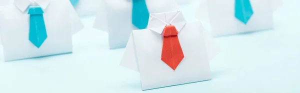 Plano panorámico de origami camisas blancas con lazos azules con un rojo, concepto de liderazgo - foto de stock