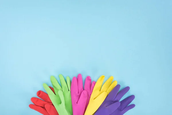 Vista superior de guantes de goma multicolores sobre fondo azul con espacio para copiar - foto de stock