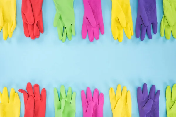 Вид сверху разноцветных ярких резиновых перчаток на синем фоне с копировальным пространством — стоковое фото