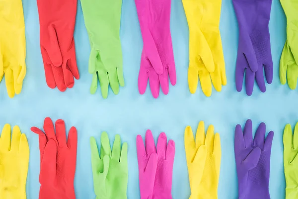 Flat lay with multicolored rubber gloves on blue background — Stock Photo