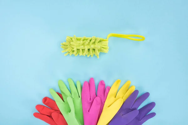 Flat lay with multicolored rubber gloves and sponge on blue background — Stock Photo