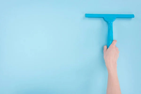 Cropped view of woman holding squeegee on blue background — Stock Photo