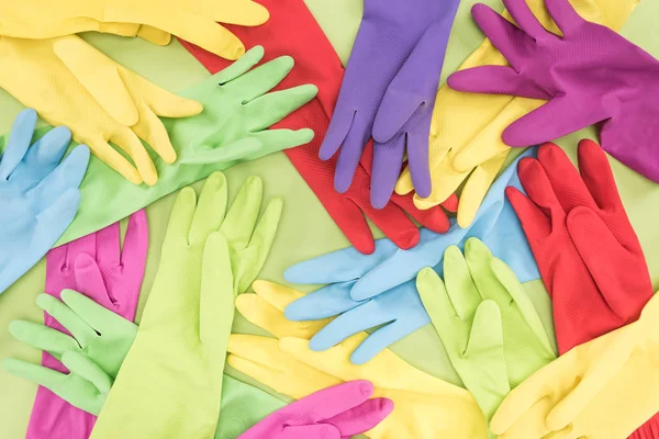 Top view of messy scattered multicolored rubber gloves on green background — Stock Photo