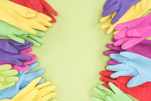 Top view of multicolored rubber gloves on green background with copy space — Stock Photo