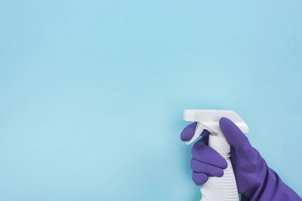 Cropped view of cleaner in purple rubber glove holding spray bottle with detergent on blue background — Stock Photo