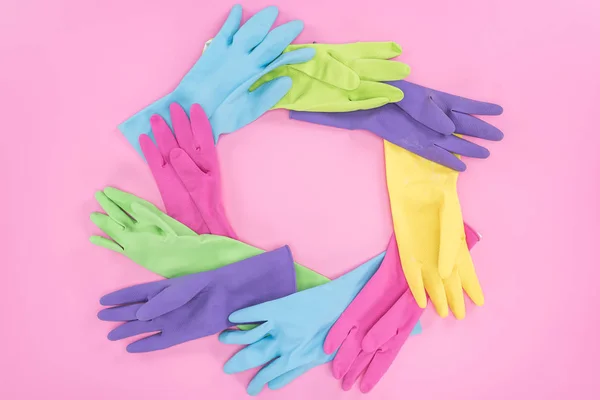 Рамка из разноцветных резиновых перчаток на розовом фоне с копировальным пространством — стоковое фото