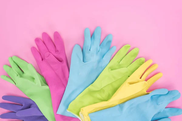 Vista superior de guantes de goma multicolores sobre fondo rosa - foto de stock