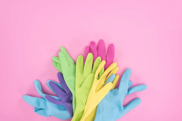 Vue de dessus des gants de caoutchouc colorés sur fond rose — Photo de stock