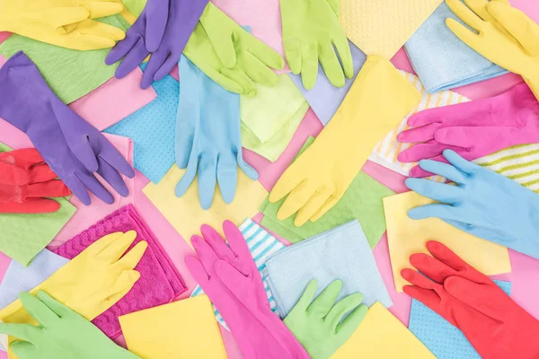 Top view of messy scattered multicolored rags and rubber gloves on pink background — Stock Photo