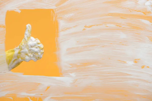 Ausgeschnittene Ansicht eines Reinigers im gelben Gummihandschuh mit Schaumstoff, der den Daumen nach oben zeigt — Stockfoto