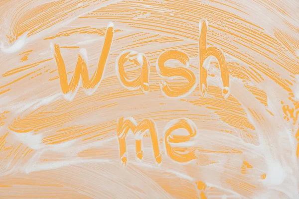 Laver moi lettrage manuscrit écrit sur verre avec mousse blanche sur fond orange — Photo de stock