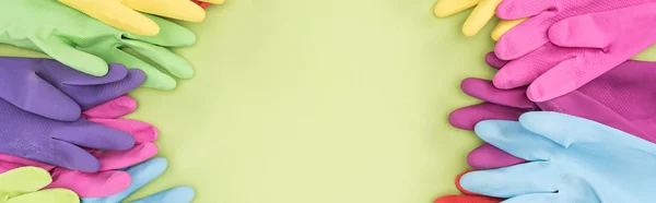 Панорамний знімок яскравих гумових рукавичок на зеленому тлі з копіювальним простором — стокове фото