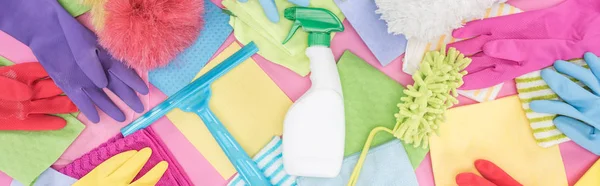 Panoramic shot of messy scattered multicolored cleaning supplies on pink background — Stock Photo