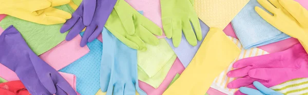 Panoramic shot of messy scattered multicolored rags and rubber gloves on pink background — Stock Photo