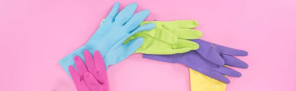 Panoramic shot of bright rubber gloves on pink background — Stock Photo