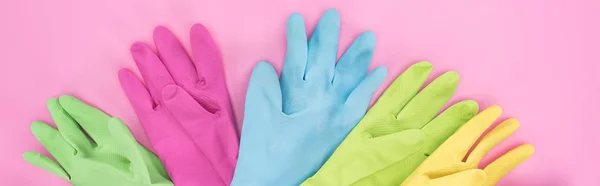 Panoramic shot of multicolored rubber gloves on pink background — Stock Photo