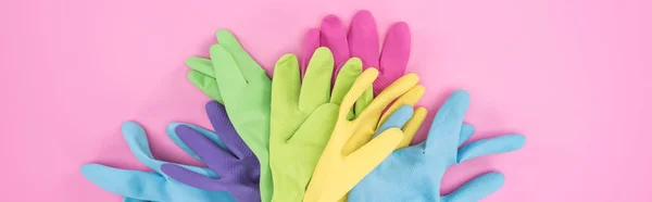 Panoramic shot of multicolored rubber gloves in pile on pink background — Stock Photo