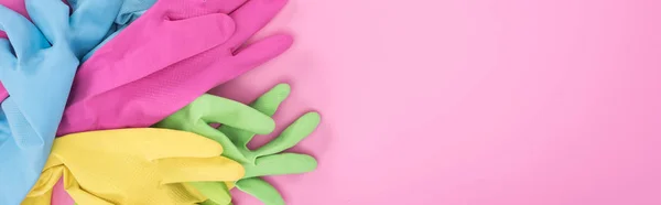 Панорамний знімок різнокольорових гумових рукавичок в купі на рожевому фоні з копіювальним простором — стокове фото