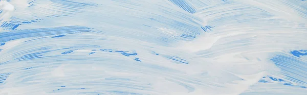 Panoramic shot of glass covered with foam on blue background — Stock Photo