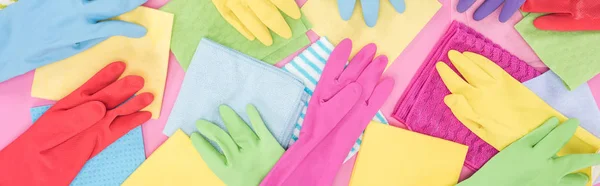 Plan panoramique de chiffons colorés éparpillés et gants en caoutchouc sur fond rose — Photo de stock