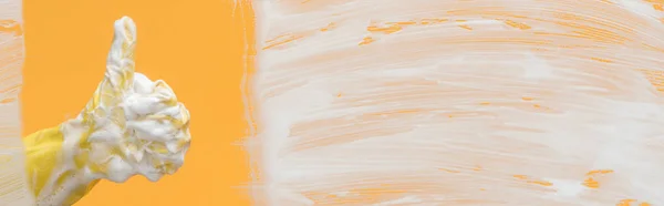 Prise de vue panoramique de nettoyant en gant de caoutchouc jaune avec mousse montrant pouce vers le haut — Photo de stock