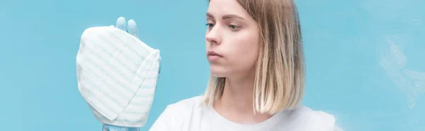 Plan panoramique de jeune femme en gant de caoutchouc nettoyage verre avec chiffon sur fond bleu — Photo de stock