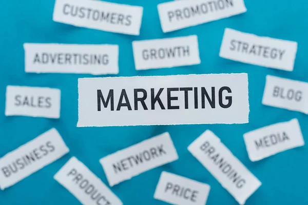 Messa a fuoco selettiva del word marketing e delle componenti del marketing su pezzi di carta blu — Foto stock