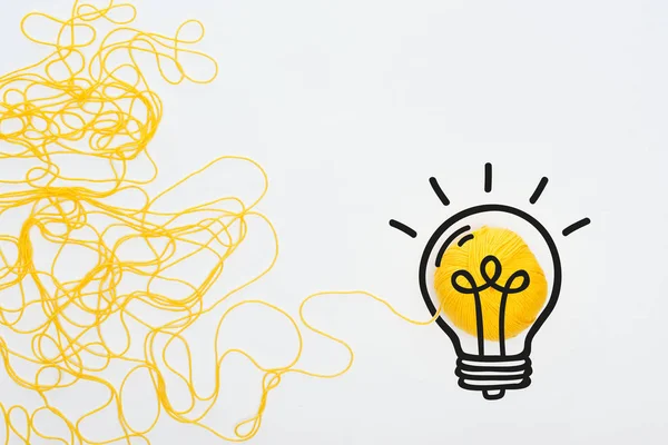 Illustration d'ampoule près de boule de tricot jaune et fil sur fond blanc, concept d'entreprise — Photo de stock